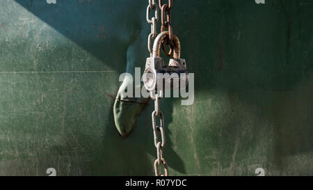 Old metal lock with a chain on green plastic background. Stock Photo