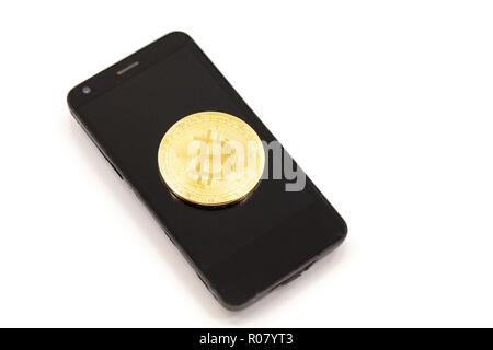 Bitcoin token on top of phone. Cryptocurrency concept with copy space. Stock Photo