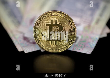 Bitcoin token on black with reflection, on top of Dubai, dirham banknotes money. Cryptocurrency versus paper currency concept Stock Photo