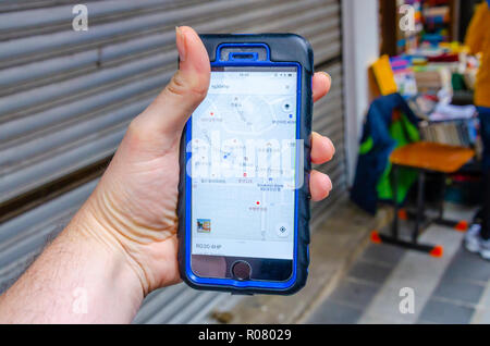 A male hand holds an iphone mobile phone and is using the Google Maps application to navigate around the city of Busan in South Korea. Stock Photo