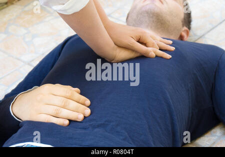 Woman doing cardiopulmonary resuscitation to a man. Stock Photo