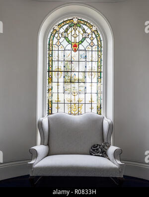Cat on armchair by stained glass window Stock Photo