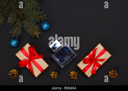 Christmas decoration. Gift boxes, bottle of cologne, fir tree branches with cones on black background. Top view. Christmas greeting card concept. Stock Photo