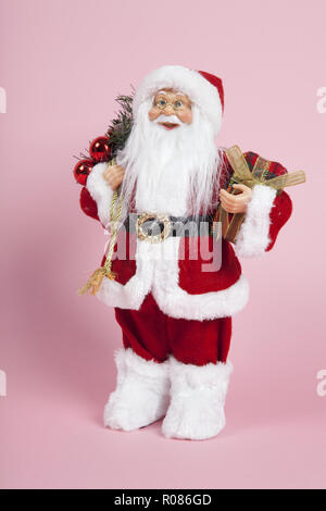 a santa claus figurine plush on a pink background. Color harmony. Minimal still life color photography Stock Photo