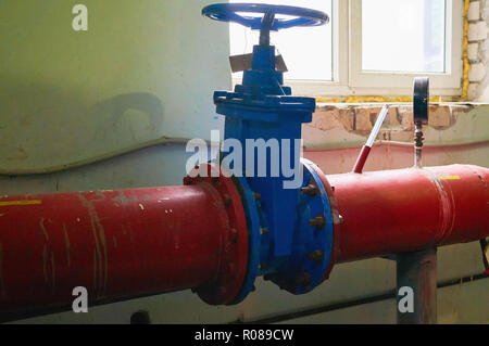 Big blue valve on the pipe painted in red color. Stock Photo