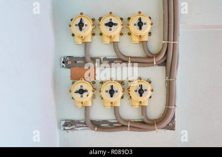 Electric switches on a white plastered wall with connected cables. Stock Photo