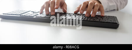 Wide view image of programmer using computer keyboard on white office desk. Stock Photo