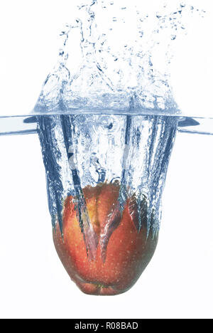 Apple falls deeply under water with a big splash. Stock Photo
