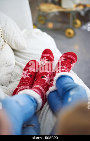 A couple laying on the sofa and wearing red christmas themed socks. Stock Photo