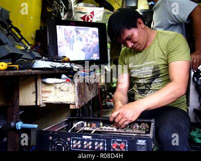 ANTIPOLO CITY, PHILIPPINES - OCTOBER 27, 2018: A repair man fixes an electronic household item at his repair shop. Stock Photo