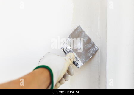 Painter working with a spatula. Process of applying layer of putty trowel Stock Photo