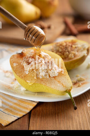 Pears with cottage cheese, nuts, honey and cinnamon on white dish. It is watered with honey. Wooden table, background blurred. Concept - Healthy food, Stock Photo