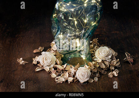 Glass head with lights inside surrounded by flowers on dark background Stock Photo