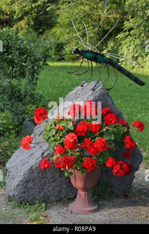 Garden decorations - stone and dragonfly plus flowers Stock Photo