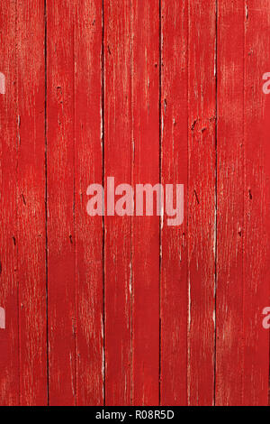 Rustic red timber door with vertical lines and peeling weathered paint. Stock Photo
