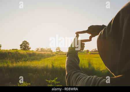 Hands making frame with sunset. Close up of woman hands making frame gesture. Stock Photo