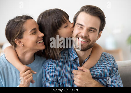 Daughter kissing father sitting together on sofa Stock Photo