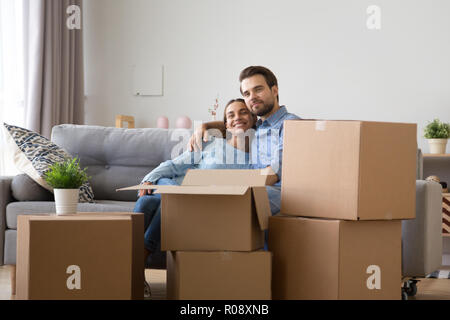 Diverse family sitting on couch at new home  Stock Photo