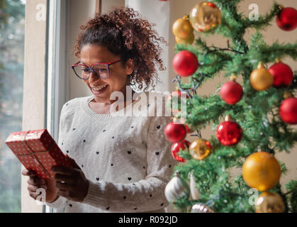 Happy black woman opening christmas presents at home