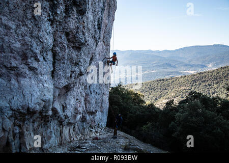 Young climber man climbing a large wall in a beautiful landscape in shadow