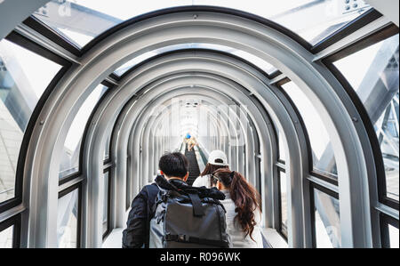 Tourists with backpack going up tunnel escalator in Umeda Sky building in Osaka, Japan Stock Photo