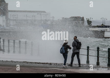 Penzance, Cornwall, UK. 3rd November 2018. UK Weather. As Storm Oscar approaches the UK and big waves hit Penzance sea front this couple were on the sea front photographing the breaking waves. Credit: Simon Maycock/Alamy Live News Stock Photo