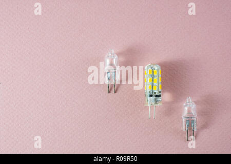 G4 bipin lamps two halogen and one modern eco LED type arranged diagonally on a pink background showing technology shift Stock Photo