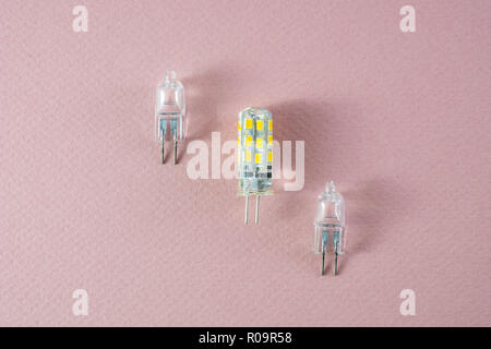 G4 bipin lamps two halogen and one modern eco LED type arranged diagonally on a pink background showing technology shift Stock Photo