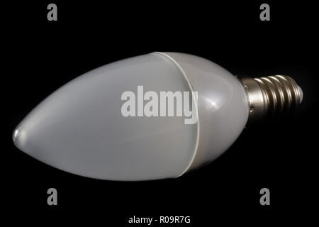 Latest modern LED light bulb in candle shape on black background demonstrating modern eco energy saving technology Stock Photo