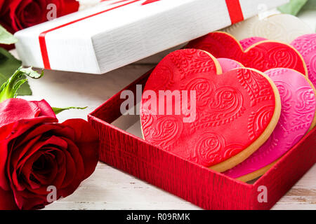 Heart-shaped cookies in gift box decorated with roses for Valentine's Day on white wooden table Stock Photo