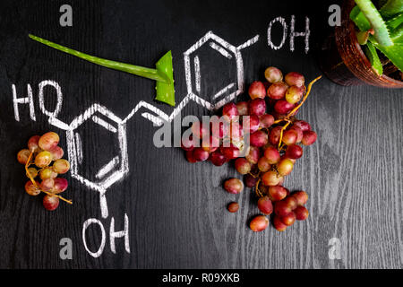 resveratrol rich red grape and green aloe slices, formula on the black wooden background Stock Photo