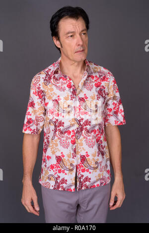 Mature handsome tourist man against gray background Stock Photo
