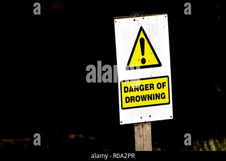 Danger of drowning sign post next to lake Stock Photo