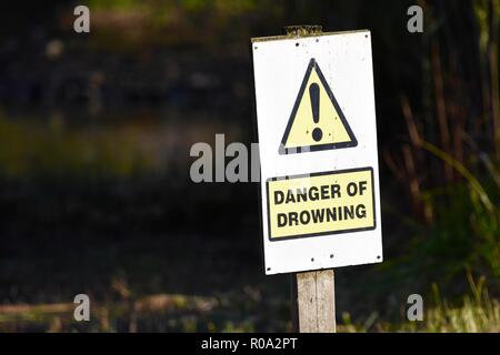 Danger of drowning sign post next to lake Stock Photo