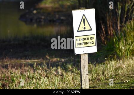 Danger of drowning sign post next to lake Stock Photo