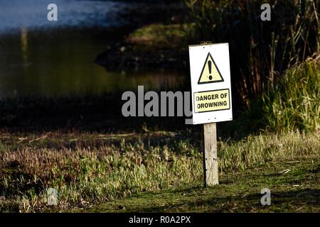 Danger of drowning sign post next to lake Stock Photo