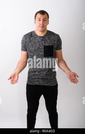 Studio shot of young muscular man standing while looking confuse Stock Photo