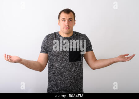 Studio shot of young muscular man looking confused against white Stock Photo