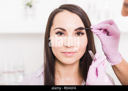 Beautiful young woman gets eyebrow correction procedure Stock Photo