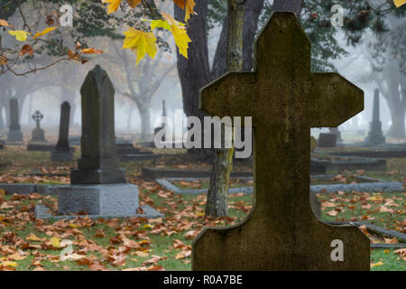 Grave markers in Ross Bay Cemetery on a foggy autumn morning in Victoria, British Columbia, Canada. Stock Photo