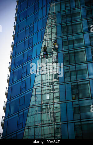 Two men washing windows on the outside of the high-rise building. Stock Photo