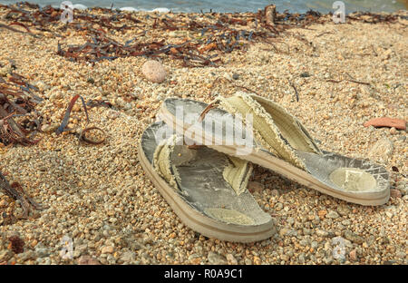 Pair of worn and worn flip-flops abandoned on the sand of the Mediterranean beach. Stock Photo