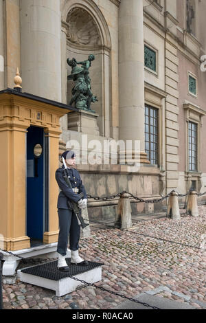 A young woman soldier stands on guard duty outside the Royal Palace (Kungliga Slottet) armed with a rifle, Gamla Stan, Stockholm, Sweden Stock Photo