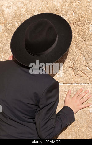 An orthodox Jewish man in a black hat praying and in deep thought at the Western Wall in the Old City, Jerusalem, Israel. Stock Photo