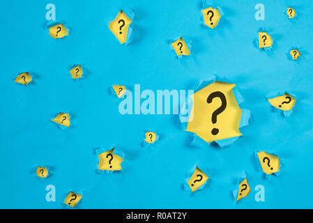 Torn blue paper revealing QUESTION MARK on yellow paper. concept of questions, faq, q&a, problem, riddle and quiz background Stock Photo