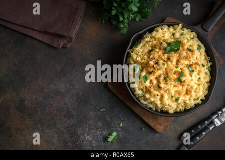 Mac and cheese, american style macaroni pasta with cheesy sauce and crunchy breadcrumbs topping on dark rustic table, copy space top view Stock Photo