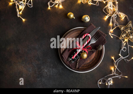 Christmas Table Setting with  lights on dark rustic table, copy space. Christmas dinner, party design, concept. Stock Photo