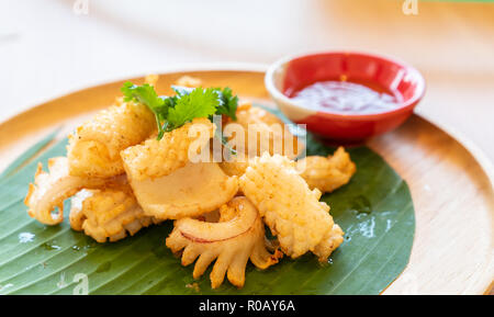 grilled dried squid, thai street seafood cuisine on banana leaf on wooden table. Stock Photo