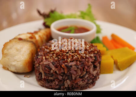 Thai Style Steamed Rice-berry Rice with Quinoa, Blurred Grilled White Seabass and Boiled Vegetables in Background Stock Photo