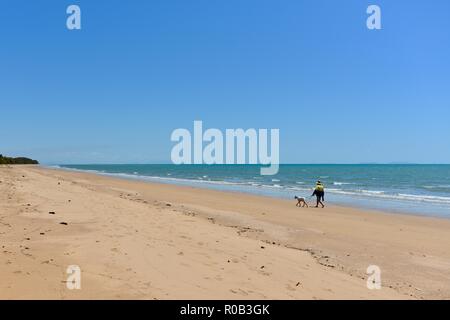 Man walking dog along deserted beach, Balgal beach, QLD, Australia Stock Photo